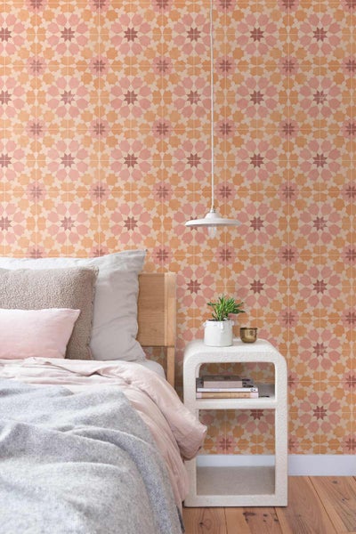 Schlafzimmer mit geometrisch gemusterter Tapete an der Wand, einem Bett mit Kissen und einem modernen Beistelltisch mit Pflanze.