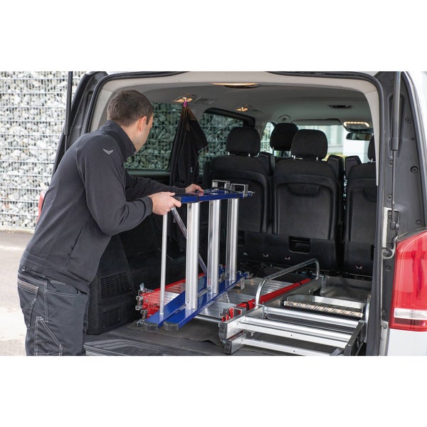 Eine Person verstaut eine Treppe im Kofferraum eines Lieferwagens.
