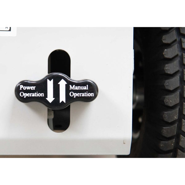 Unterseite eines grauen Transportgeräts mit roten Lenkrollen, schwarzen Rädern und elektrischen Komponenten.