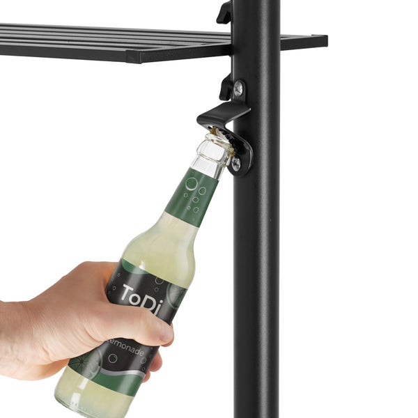 Ein Flaschenöffner aus Metall, montiert an einem schwarzen Regalbein, wird zum Öffnen einer Getränkeflasche verwendet.