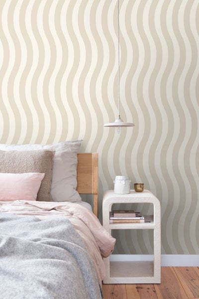 Vliestapete mit beigem Wellenmuster in einem hellen Schlafzimmer mit Holzbett, modernem Nachttisch und Pendelleuchte.