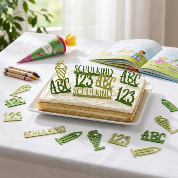 Ein Blechkuchen mit Tortenaufsteckern in Form von Schultüten, Buchstaben und Zahlen zur Einschulung auf einem gedeckten Tisch.