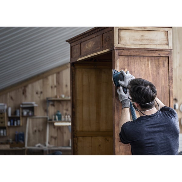 Mann schleift einen Holzschrank mit einem Schleifgerät ab