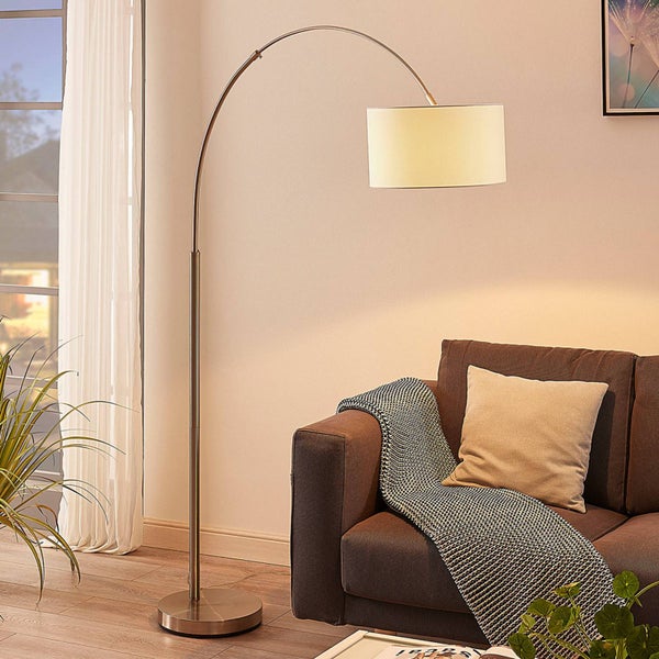 Bogenlampe neben braunem Sofa mit Kissen und Decke im Wohnzimmer
