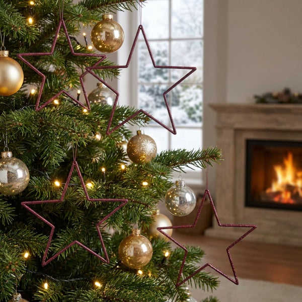Weihnachtsbaum mit glitzernden Sternen zum Aufhängen und Christbaumkugeln vor einem Kamin im Hintergrund.