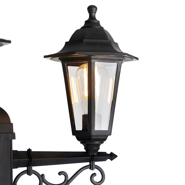 Klassische Außenwandleuchte aus schwarzem Metall mit klaren Glasscheiben und einem leuchtenden LED-Leuchtmittel im Filament-Stil.
