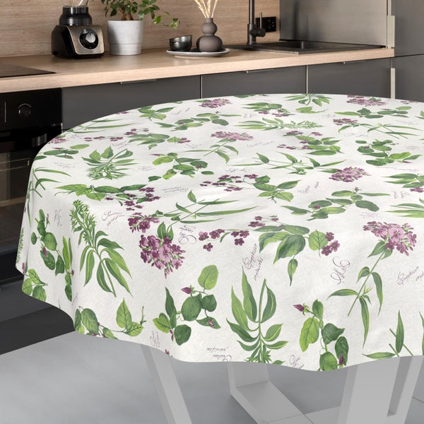 Runde Tischdecke mit botanischem Muster aus lila Blumen und grünen Blättern auf einem Tisch in einer modernen, hellen Küche.