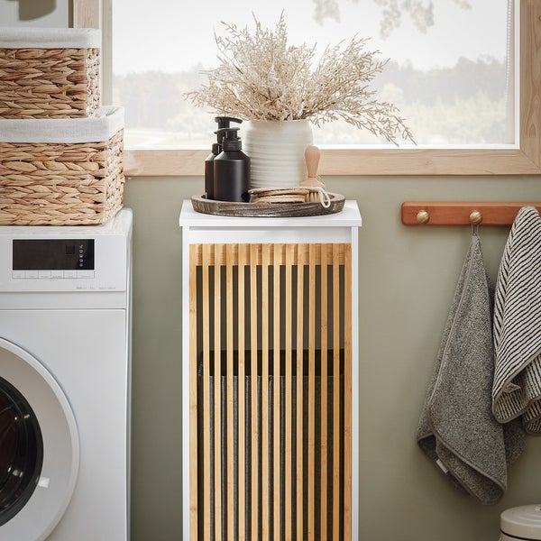 Badezimmer Szene mit einem weißen Unterschrank mit Bambusfront, Waschmaschine und Dekorationsartikel