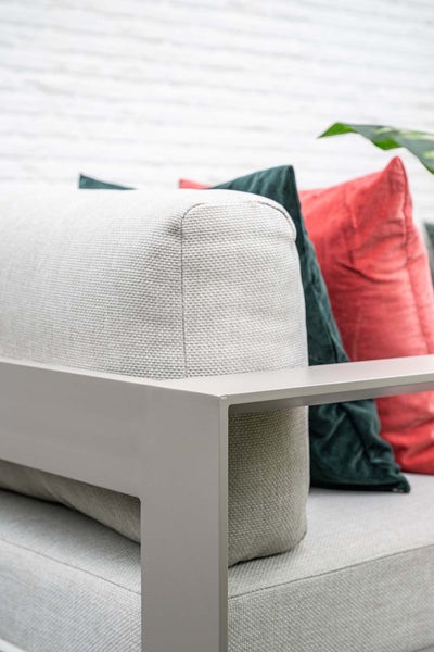 Detailansicht eines Gartensofas mit Aluminiumrahmen, hellen Polstern und bunten Zierkissen.