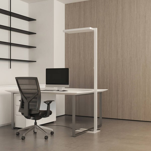Modernes Büro mit weißem Schreibtisch, schwarzem Bürostuhl und einer schlanken, weißen LED-Stehleuchte vor einer Holzwand.