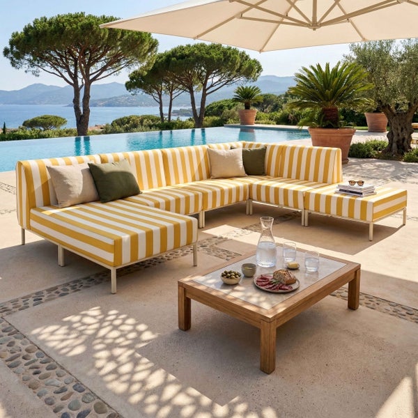 Modernes Garten-Lounge-Set mit gelb-weiß gestreifter Polsterung, Holz-Couchtisch und Hocker auf einer Terrasse mit Pool und Meerblick.