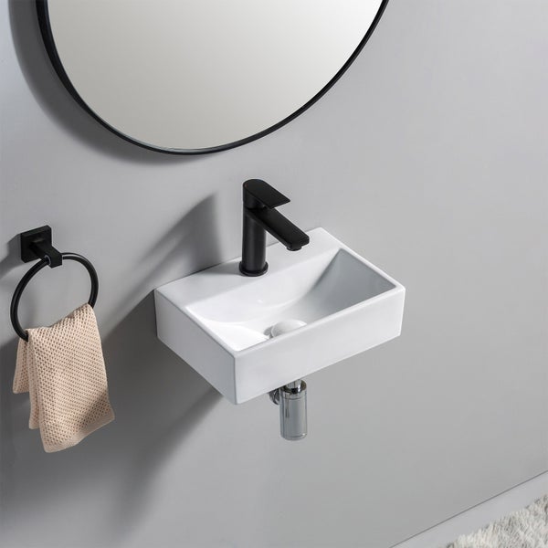 Ein kleines, wandhängendes Waschbecken mit Armatur, Handtuchring und Spiegel im modernen Bad.