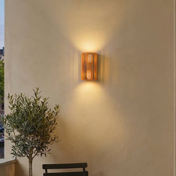 Moderne Wandleuchte aus Holz mit nach oben und unten gerichtetem Licht an einer Wand mit einer kleinen Topfpflanze.