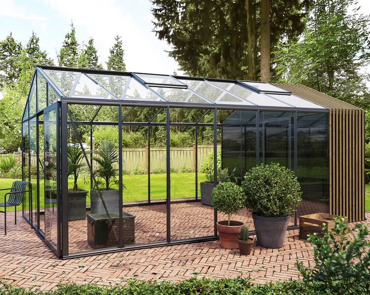 Modernes Gewächshaus aus Glas mit schwarzem Aluminiumrahmen und Holzlamellen auf einer Ziegelterrasse im Garten.