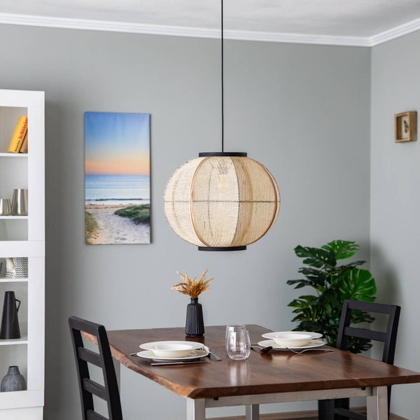 Modernes Esszimmer mit großer runder Pendelleuchte aus Naturgeflecht über einem Holztisch mit Gedecken und Stühlen.