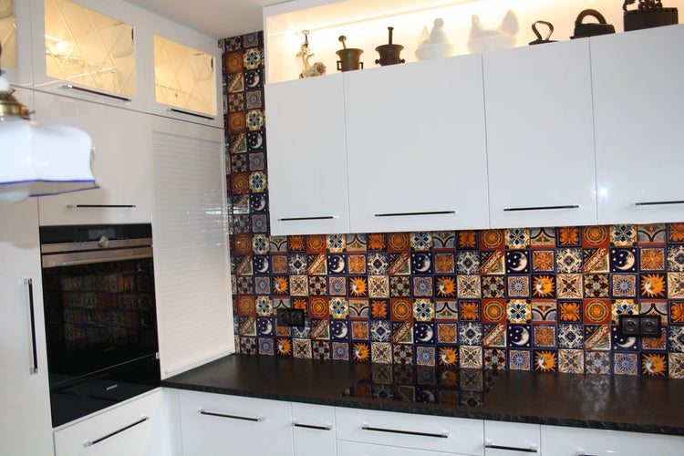 Küchenszene mit weißen Schränken, dekorativen Fliesen und dunkler Arbeitsplatte