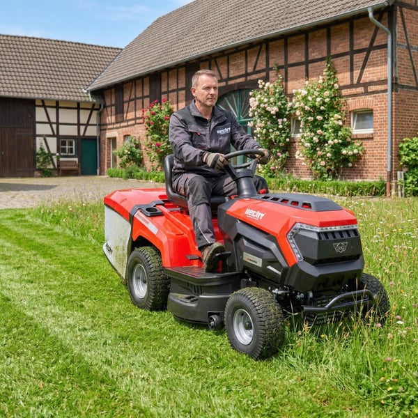 Mann fährt Rasentraktor auf Rasen vor einem Haus