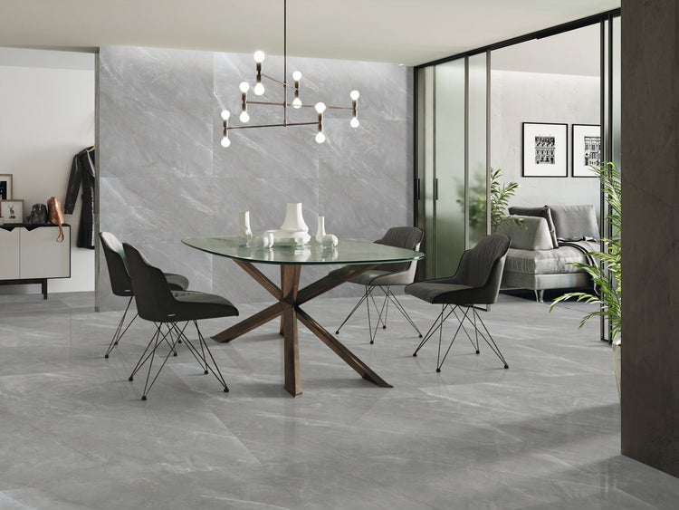 Heller und geräumiger Raum mit Esstisch, Stühlen und grauen Bodenfliesen in Marmoroptik.