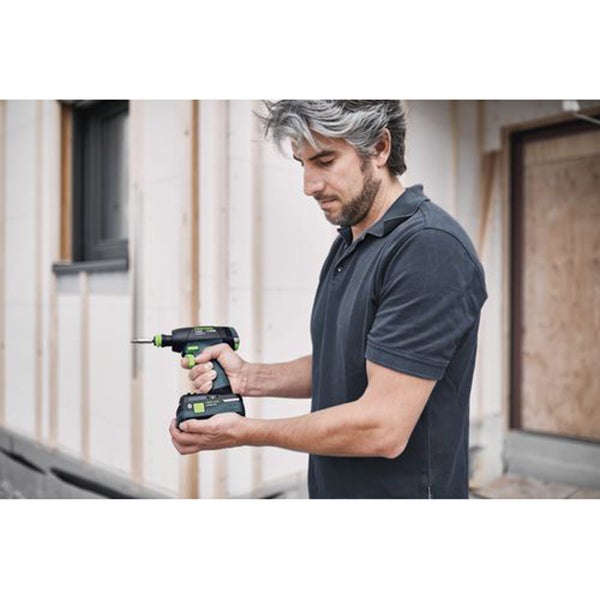 Ein Handwerker hält einen Akku-Schrauber von Festool vor einer Baustelle.