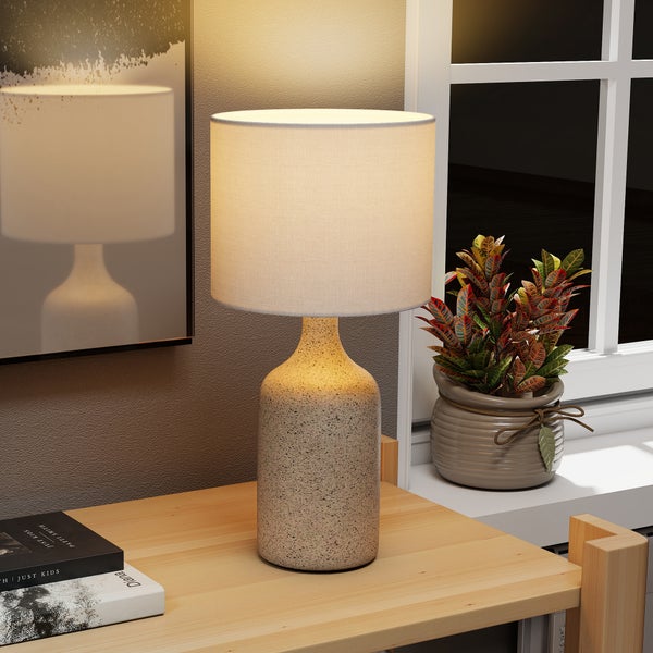 Dekorative Tischleuchte mit Lampenschirm und Zimmerpflanze auf einem Holztisch