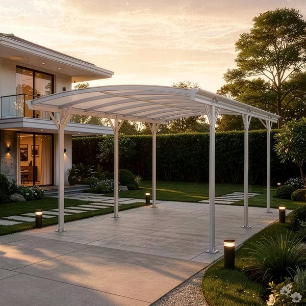 Moderner weißer Carport aus Aluminium mit gewölbtem Dach auf einer gepflasterten Fläche in einem Garten neben einem Haus.