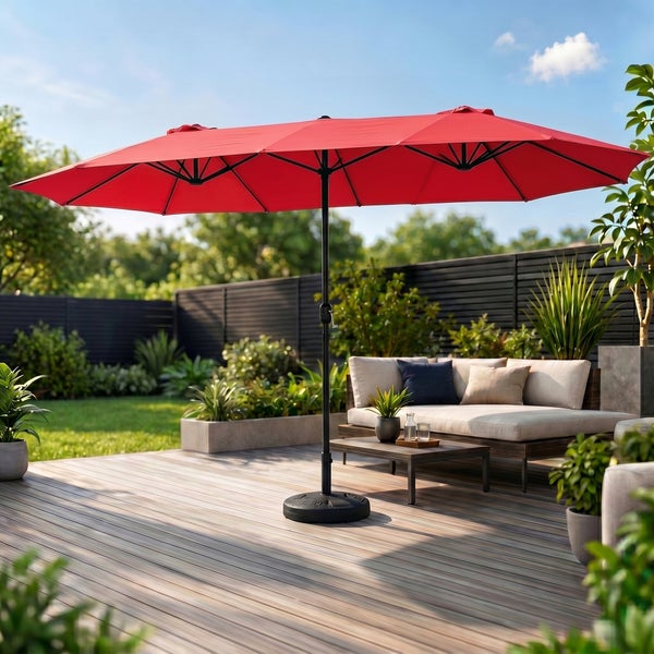 Großer roter Doppel-Sonnenschirm auf einer Holzterrasse mit Loungemöbeln, Topfpflanzen und dunklem Zaun im hellen Garten.