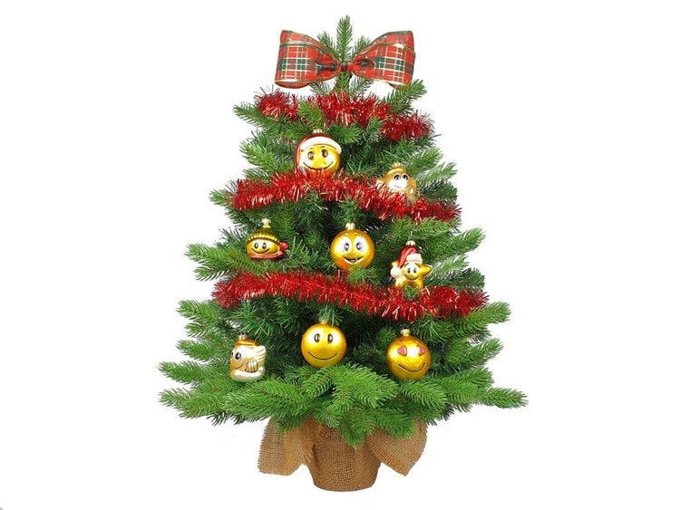 Geschmückter künstlicher Weihnachtsbaum mit Emoji Christbaumkugeln und roter Girlande im Jutesack.