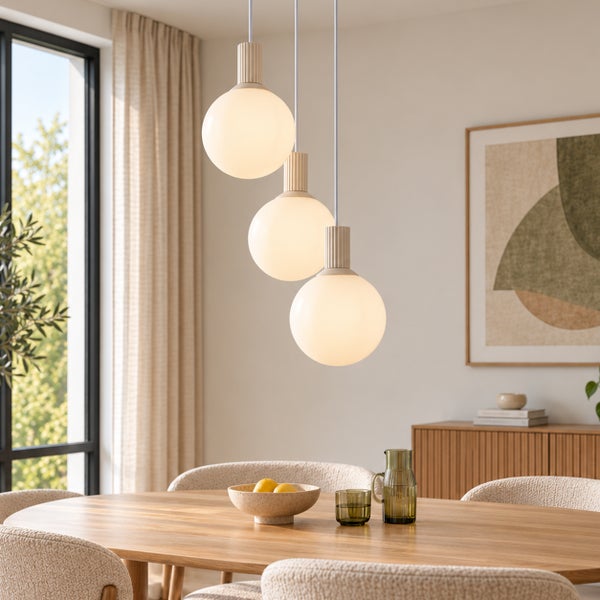 Moderne Pendelleuchte mit drei kugelförmigen Glasschirmen über einem Holzesstisch in einem hellen und stilvoll eingerichteten Esszimmer.