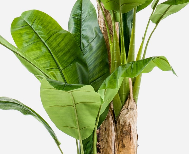 Künstliche Bananenpflanze mit großen grünen Blättern und realistischem Stamm in Nahaufnahme.
