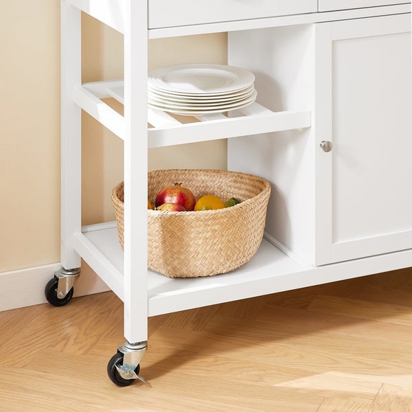 Detailansicht eines weißen Küchenwagens mit Rollen, Ablageflächen, Geschirr und einem Korb mit Obst.