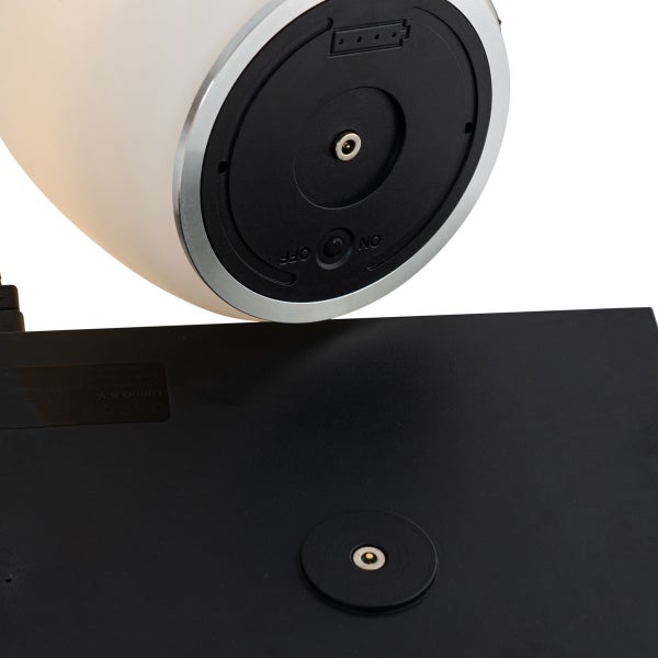 Unterseite einer tragbaren Lampe mit Ein-Aus-Schalter und Ladekontakt über einer schwarzen Ladestation.