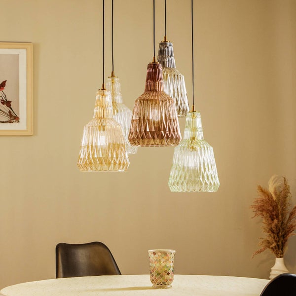 Fünfflammige Pendelleuchte mit facettierten Glasschirmen in verschiedenen Farben über einem Esstisch in einem hellen, modernen Zimmer.