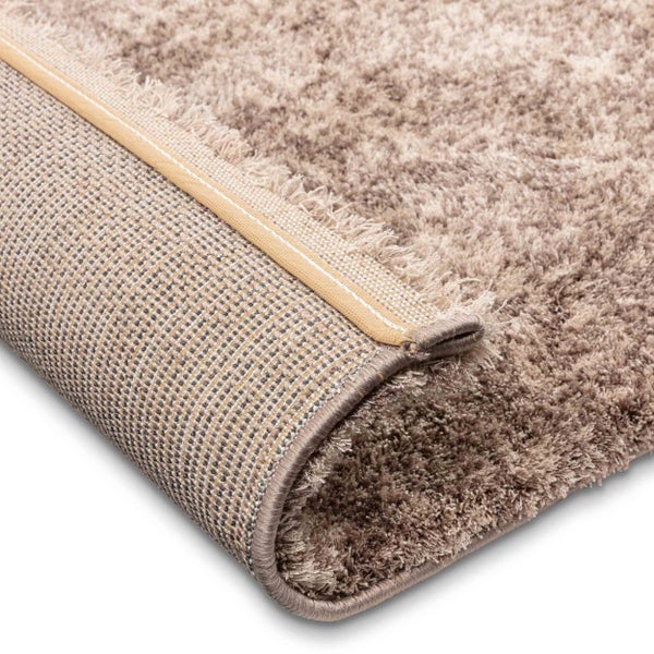 Beigefarbener Hochflor Teppich mit weicher Oberfläche und gewebter Rückseite.