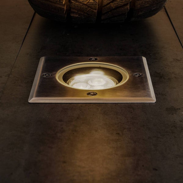 Quadratischer LED Boden-Einbaustrahler aus Edelstahl, in eine dunkle Bodenfliese eingelassen, eingeschaltete Beleuchtung.