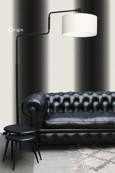 Wohnzimmer mit Ledersofa, Stehlampe und Beistelltischen vor einer gemusterten Tapete