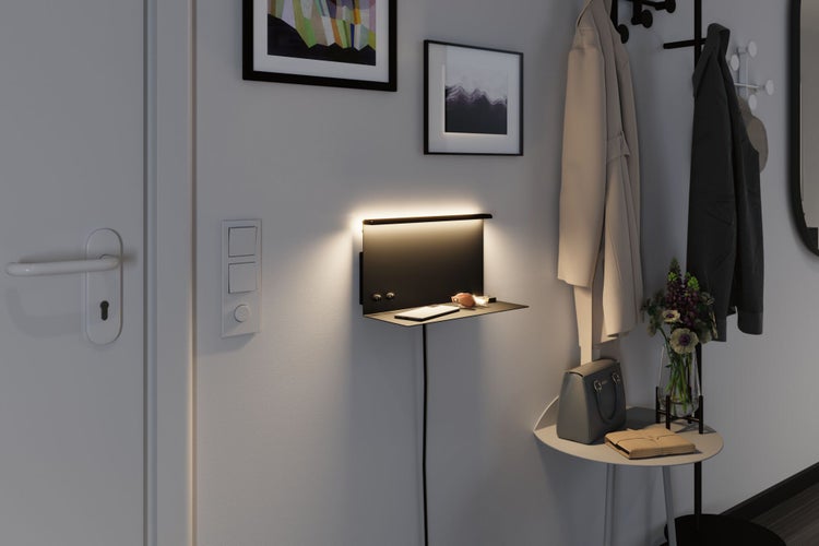 Modern beleuchtete Wandablage mit integrierter Lichtleiste in einem Flur neben einem Lichtschalter und einer Garderobe.