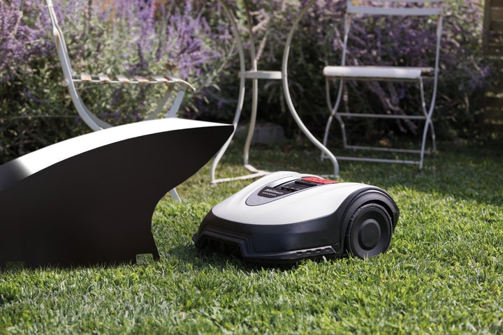 Mähroboter auf Rasenfläche mit Gartenmöbeln im Hintergrund