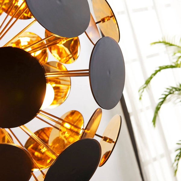 Nahaufnahme einer modernen Deckenleuchte mit runden Scheiben in Schwarz und Gold an filigranen Metallstäben.