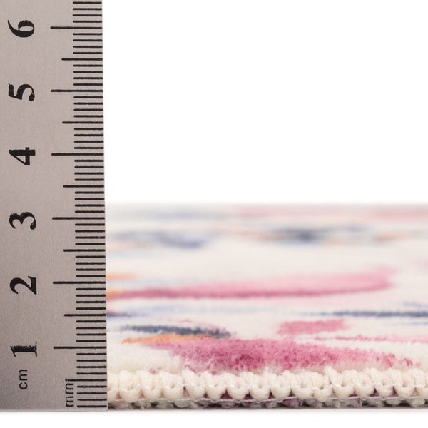Nahaufnahme der Florhöhe eines gemusterten Teppichs, gemessen mit einem Lineal, circa 1 Zentimeter dick.