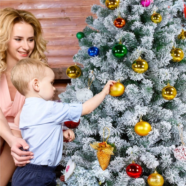 Mutter und Kind schmücken einen Weihnachtsbaum mit Weihnachtskugeln.