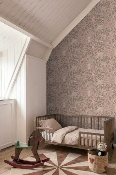 Vliestapete mit floralem Wiesenmuster in einem hellen Kinderzimmer mit Holzbett, Schaukelpferd und Dachschräge.