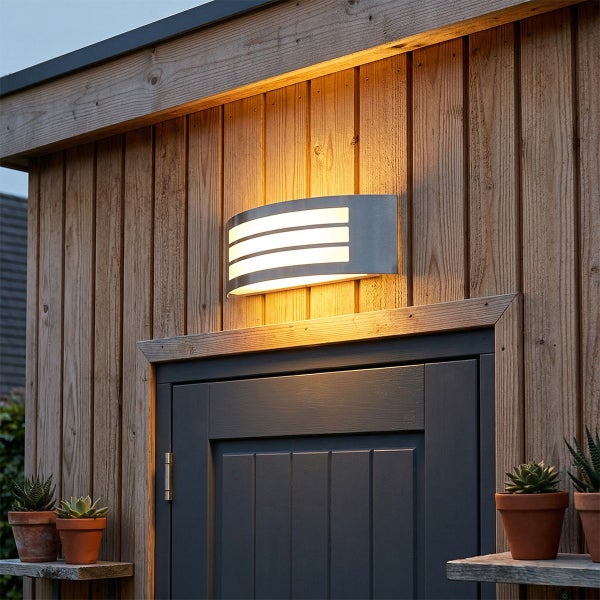 Moderne Außenwandleuchte aus Edelstahl mit horizontalen Lichtschlitzen, montiert an einer Holzwand über einer Tür.