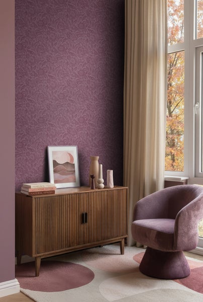Modernes Wohnzimmer mit Vliestapete in Beerentönen mit floralem Muster, Holzsideboard und violettem Samtsessel.