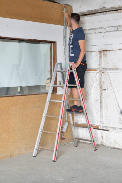 Mann auf einer Aluminium-Leiter bei Elektroarbeiten in Innenräumen