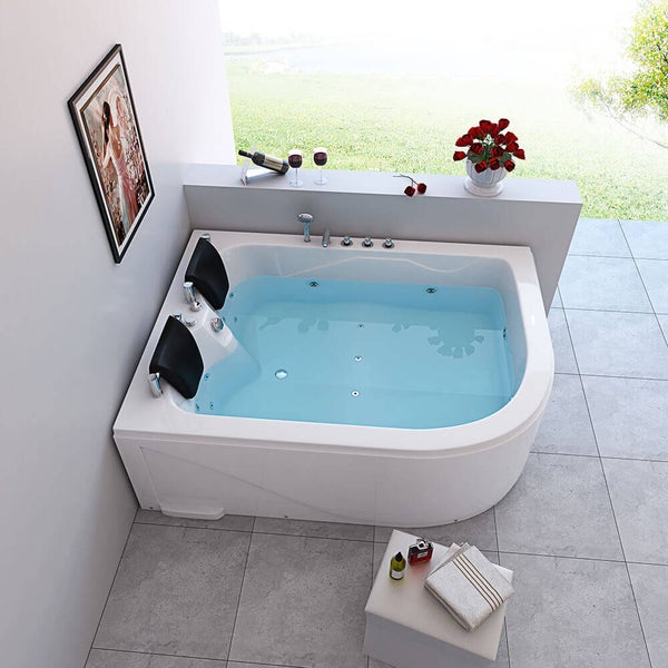 Eck-Whirlpool mit zwei Kopfstützen und integrierten Armaturen in einem modernen, hellen Badezimmer mit Fliesenboden.