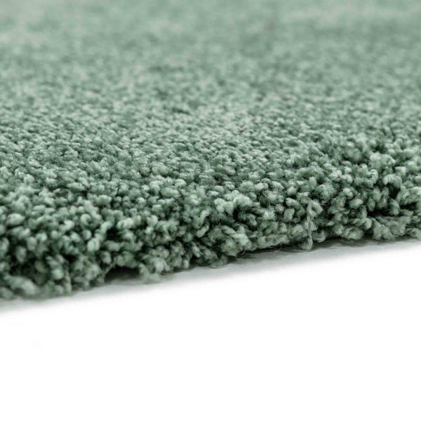 Grüner Hochflor-Teppich mit weicher Struktur in Nahaufnahme.