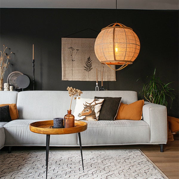 Wohnzimmer mit runder Stoffhängelampe, hellem Sofa, Holztisch und dekorativen Accessoires in einem gemütlichen Einrichtungsstil.