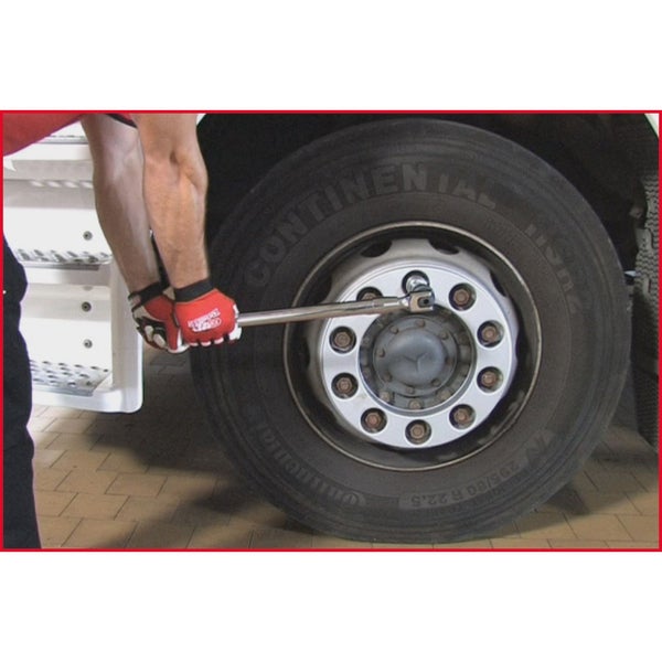 Eine Person wechselt mit einem Steckschlüssel einen Reifen an einem Lastkraftwagen.