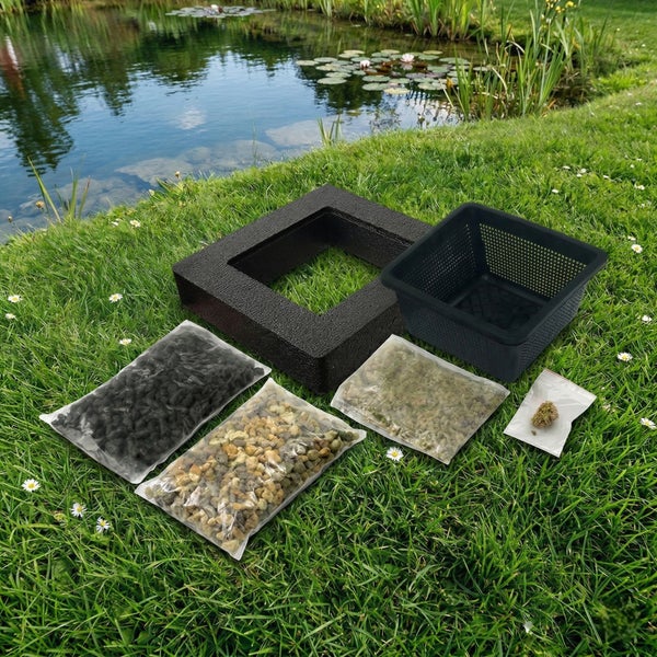 Schwimminsel Set für Teichpflanzen mit Schaumstoffrahmen, Pflanzkorb, Kies, Substrat und Samen auf einer Wiese an einem Gartenteich.