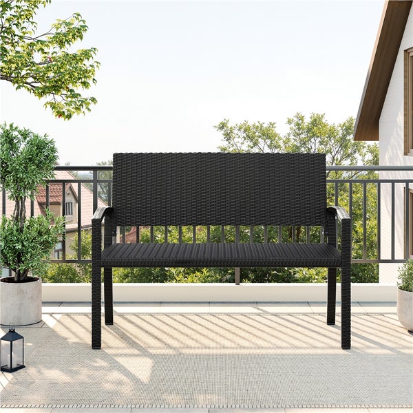 Moderne Gartenbank aus Polyrattan auf einem hellen Balkon mit Pflanzen und Geländer.